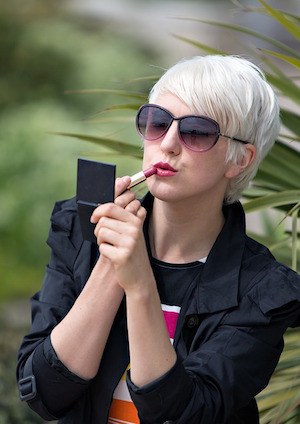 What does watching a reality show say about you? Photo of woman applying lipstick in a mirror